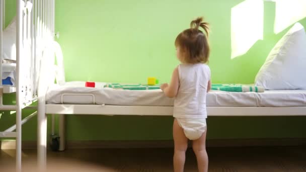 Kleine baby draait rond ziekenhuis kamer en lacht. Meisje herstelt in ziekenhuis — Stockvideo