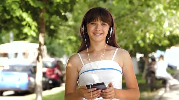 Girl in headphones with tablet is smiling in city — Stock Video