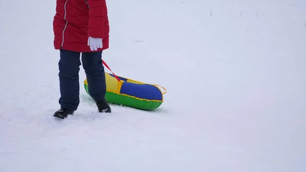 Adolescente sube a la montaña nevada de invierno sosteniendo platillo de nieve. Juegos de invierno al aire libre. Navidad — Foto de Stock