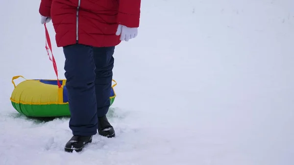 Adolescente sube a la montaña nevada de invierno sosteniendo platillo de nieve. Juegos de invierno al aire libre. Navidad — Foto de Stock