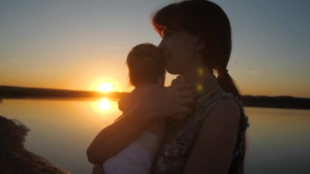Mamá sostiene al niño en brazos de sol al atardecer. Movimiento lento . — Vídeo de stock