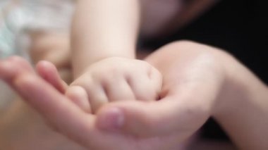 Annesi elini avucunun içinde küçük bebeği tutar.