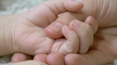 Anne küçük bebeğin elini tutuyor. Küçük çocuk anne bakımı. Yakın çekim