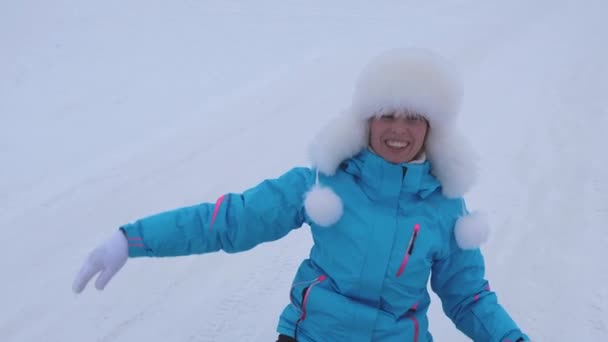 Glad tjej rullar från höga snötäckta berg och skrattar. Kvinna kälkåkning på vintern och leende. Jul — Stockvideo