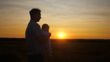 Bebek babasının günbatımında ellerinizde. Ağır çekim.