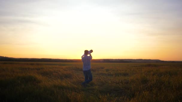 O pai brinca com o bebé, de helicóptero, ao pôr-do-sol. Movimento lento . — Vídeo de Stock