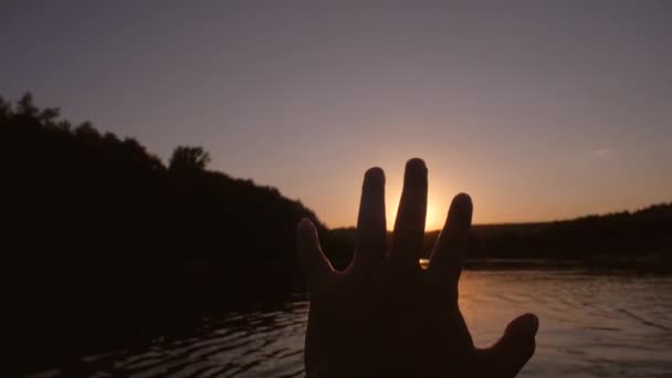 Mans palm touches sun, sunset against background of river — Stock Video