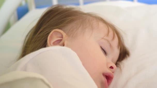 Μωράκι κοιμάται στο νοσοκομείο ward λευκά κλινοσκεπάσματα. Θεραπεία των παιδιών σε νοσοκομειακό περιβάλλον. Άρρωστο παιδί βελτιώνει την υγεία του στο νοσοκομείο — Αρχείο Βίντεο