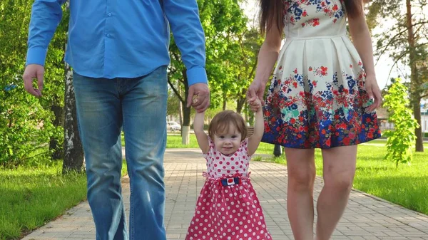 Lilla barnet lära sig att gå med mamma och pappa, lycklig familj promenader i sommaren Park — Stockfoto