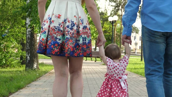 Kleine baby leren hoe om te lopen met pappa en mamma, wandelen in de zomer Park en gelukkige familie — Stockfoto