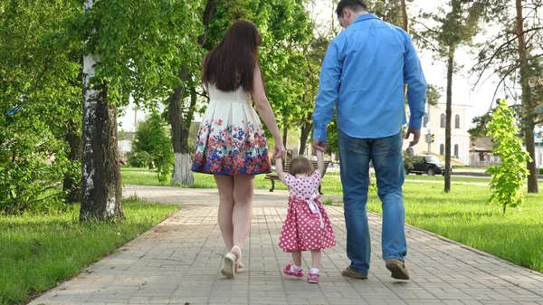 Bebé aprendiendo a caminar con mamá y papá, familia feliz caminando en el parque de verano — Foto de Stock