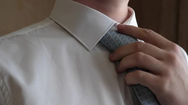 Manos del hombre enderezando corbata azul en camisa blanca. por la mañana un hombre se viste para ir a trabajar. primer plano —  Fotos de Stock