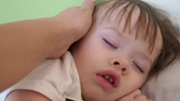 Anya ellenőrzi hőmérsékletét kezével a homlokához kis baba alszik — Stock videók