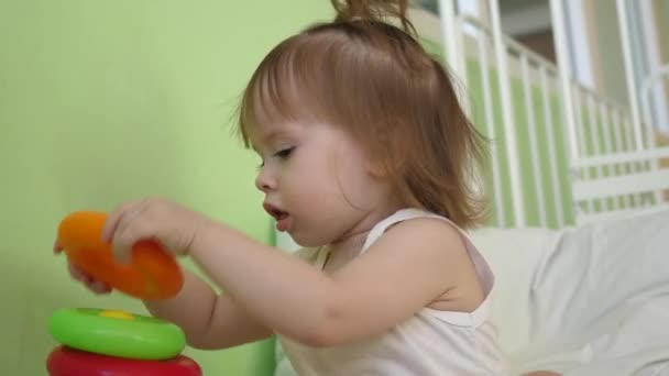 Pequeño juego de bebé en la cama con pirámide y anillos de colores. Juguetes educativos para niños de preescolar y jardín de infantes. Juguete para niñas — Vídeos de Stock