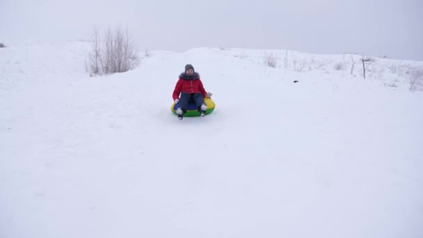 Chica feliz paseos con alta nieve platillo de nieve de montaña y se ríe. Niño en trineo en invierno y sonriendo. Resort de montaña. Vacaciones de Navidad — Vídeos de Stock