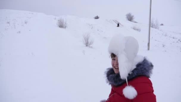 Ragazza felice cavalca con piattino di neve e ride. Bambino slittino in inverno e sorridente. Località di montagna. Vacanze di Natale — Video Stock