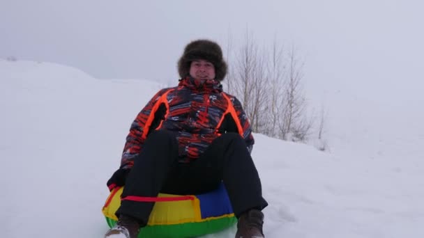 Uomo felice cavalca con piattino di neve e ride. Uomo slittino in inverno e sorridente. Località di montagna. Vacanze di Natale — Video Stock