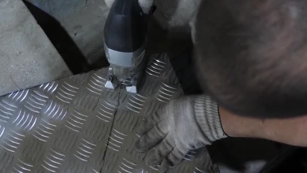 Werknemer in beschermende bril saws een glanzende ijzer blad met een elektrische jig saw in witte beschermende handschoenen. van bovenaf bekijken — Stockvideo