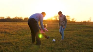 Gün batımında futbol topu parkta genç bebekle oynamaktan aile. Mutlu baba ve çocuk topu tekmelemek. mutlu aile kavramı. Ağır çekim