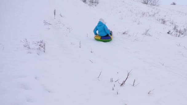 Chica paseos de alta montaña en platillo de nieve sobre la nieve en invierno y se ríe de placer. Mujer alegre en trineo. Navidad — Vídeo de stock