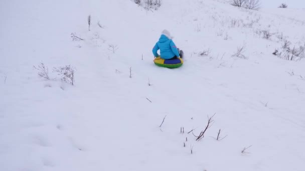 Girl rides from high mountain on snow saucer over snow in winter and laughs with pleasure. Cheerful woman sledding. Christmas — Stock Video