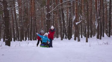 Çocuk Anne çam parkı ve gülmek karlı yol boyunca kar daire rulo. İğne yapraklı orman kışın oynama ve gülümseyerek mutlu bir aile. Anne ve kızı hafta sonu dinlenmek. Noel tatili