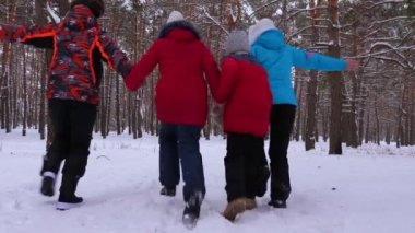Çocuklar, anne ve baba karlı kış orman ve gülmek çalıştırın. Erkek ve kadın kızları ile birlikte parkta kışın eğleniyorlar. Noel hafta sonu
