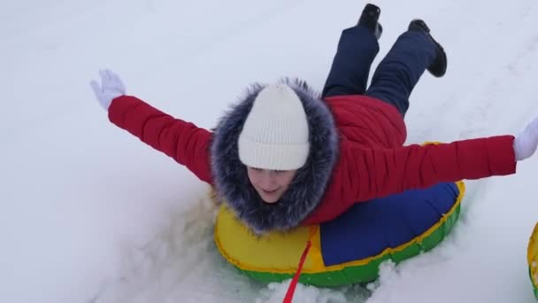 Meninas adolescentes rolam em passeio de trenó ao longo da estrada branca de neve no inverno. Namoradas montam disco de neve na neve. Férias de Natal — Vídeo de Stock