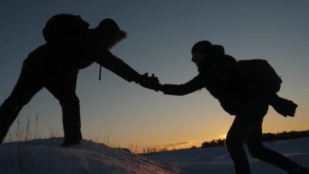 Männer helfen einander, den Gipfel des hohen schneebedeckten Berges zu bezwingen, indem sie sich an den Händen halten und sich bei Sonnenuntergang nach oben strecken. kalte natürliche Bedingungen auf Reisen. Extremwanderungen für Mutige — Stockvideo