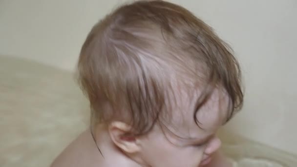 Маленька дитина у ванній з чистою водою, гризе іграшкову качку і натирає очі . — стокове відео