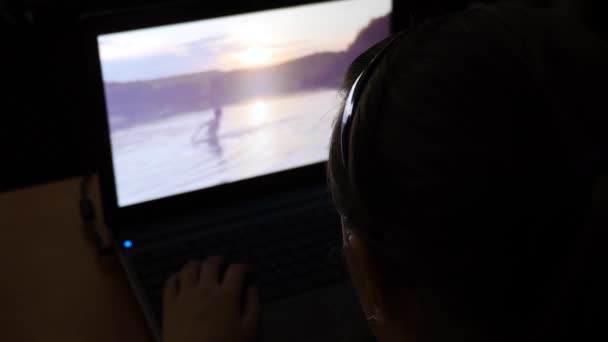Chica está mirando fotos en el portátil por la noche . — Vídeos de Stock