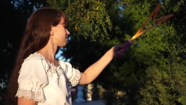 Frau pustet große Seifenblasen und lacht beim Spazierengehen im Park. Sommerspaziergänge und Spiele in der Natur — Stockvideo