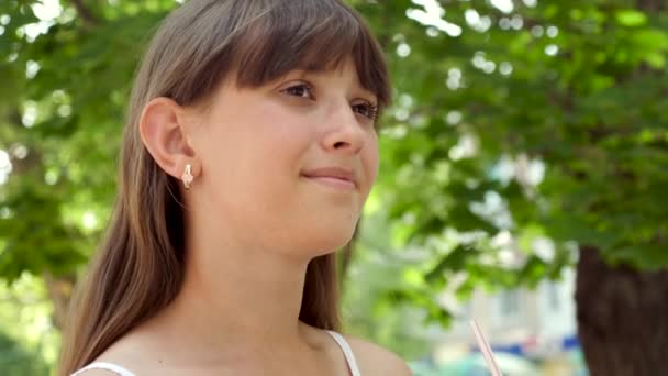 Chica está bebiendo delicioso batido de pajitas en el parque de la ciudad. Primer plano — Vídeos de Stock