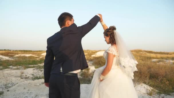 Свадебный танец в медовый месяц. Романтичный мужчина и женщина танцуют в песке на фоне неба — стоковое видео