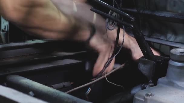 Чоловік ремонтує механізм автомобіля, стискаючи гайку з ключем ручного гальма. Фахівець працює на роботі. Крупним планом — стокове відео