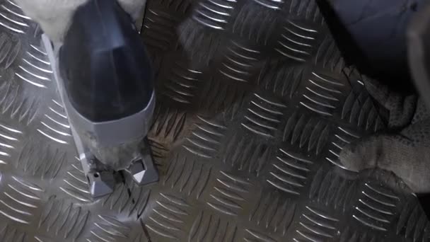 Man locksmith i cuts shiny iron sheet with an electric jigsaw. Close-up — Stock Video