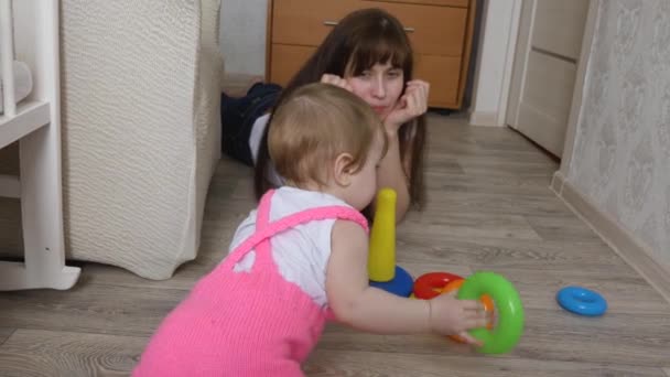 Kleines Kind spielt mit seiner Mutter buntes Spielzeug und krabbelt auf dem Boden — Stockvideo