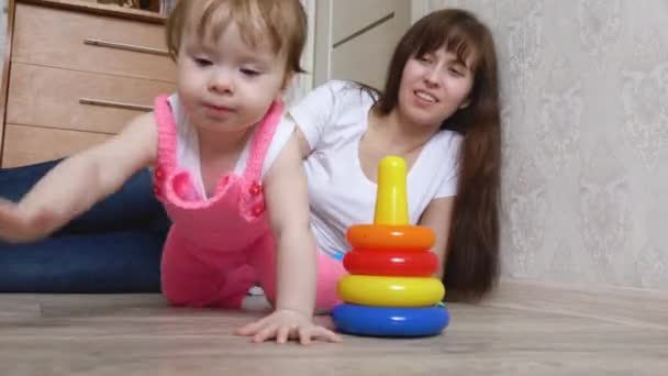 Pequena criança brinca com sua mãe coloridos brinquedos e rasteja no chão, close-up — Vídeo de Stock