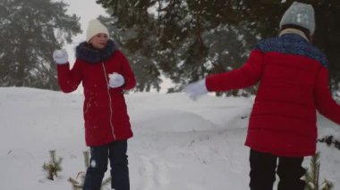 Mutlu çocuk çam parkı içinde karlı beyaz dağda kartopu oynamak. Kar kış orman ve gülümseme ile genç kız oyun