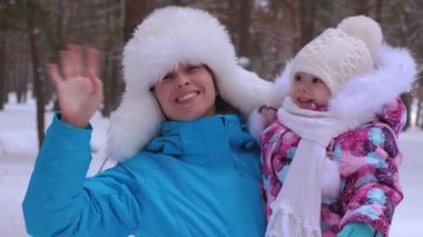 Annem onun küçük kızı şapka ve dalgalar gülümsediğini el düzeltiyor. Çocuk kış yürüyüş ile mutlu kadın gülüyor. Anne Doğum izni. Noel tatili.
