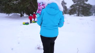 Dadı kış park çocukları ile yürür. Büyük aile halletme dinleniyor. Genç kız halletme gidin. Anne küçük bebek taşıyor