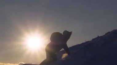 Dağcı parlak güneş ışınlarının karlı dağda tırmanıyor. turist başına güzel gökyüzü arka plan üzerinde tırmanmaya yapar. adam en üst başarısı için taşınır..