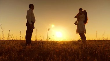Küçük kızı annesine onun kollarında günbatımında gider. Mutlu anne hugs ve bebeği öper. Baba, anne ve bebek için yürüyüş akşam oynuyorlar. İlk adımlar