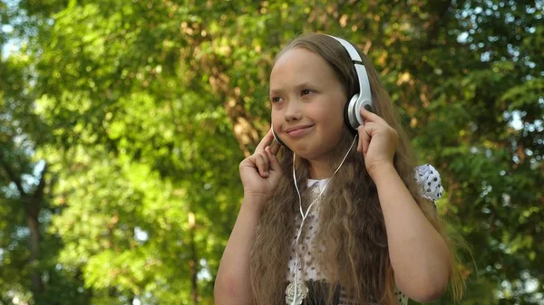 Chica en auriculares escuchando música y bailando sonriente en el parque de verano — Foto de Stock