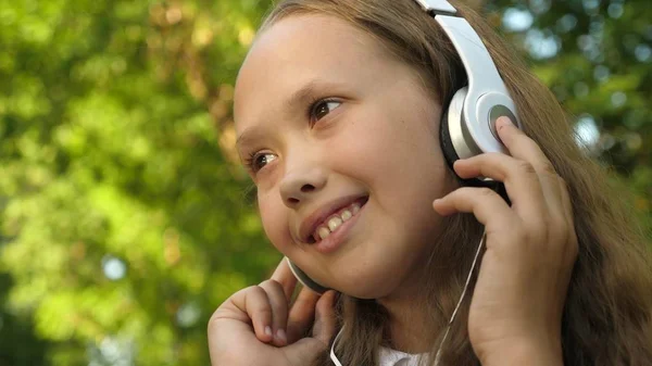 Mädchen mit Kopfhörern hört Musik und lächelt beim Tanzen im Sommerpark — Stockfoto