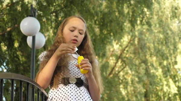 Dívka nafoukne mýdlové bubliny a úsměvů v letním parku. — Stock fotografie