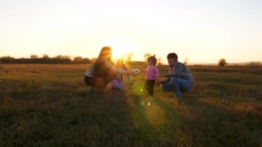 Anne küçük kızı bebek topu ile oynar. Küçük çocuk çocuklarla ve annemle top oynuyor. Gün batımında parkta bir çocuk futbol topu küçük çocuk ile oynayan aile. Yavaş çekim