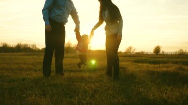 Anne ve baba bebekle oynuyor. ebeveynler gün batımı ışınlarında bebeklerin ellerini yükseltmek. aile mutluluğu kavramı. mutlu çocuk baba ve anne ile parkta atlama.