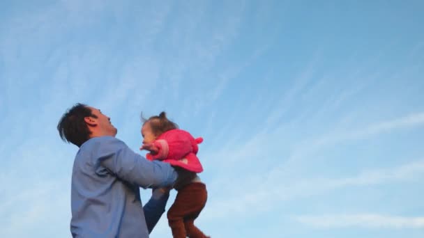 Konzept der glücklichen Familie. Papa wirft Baby hoch gegen den Himmel. Papa spielt mit seiner kleinen Tochter im Park. Vater warf Baby in blauen Himmel. — Stockvideo