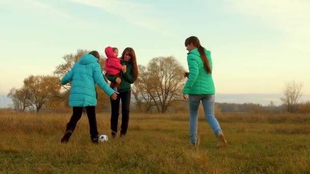 Glückliche Kinder und Mutter mit kleinem Kind spielen Fußball auf dem Feld. Familie spielt Kinderfußball im Park. Zeitlupe. Sportliches Familienkonzept — Stockvideo